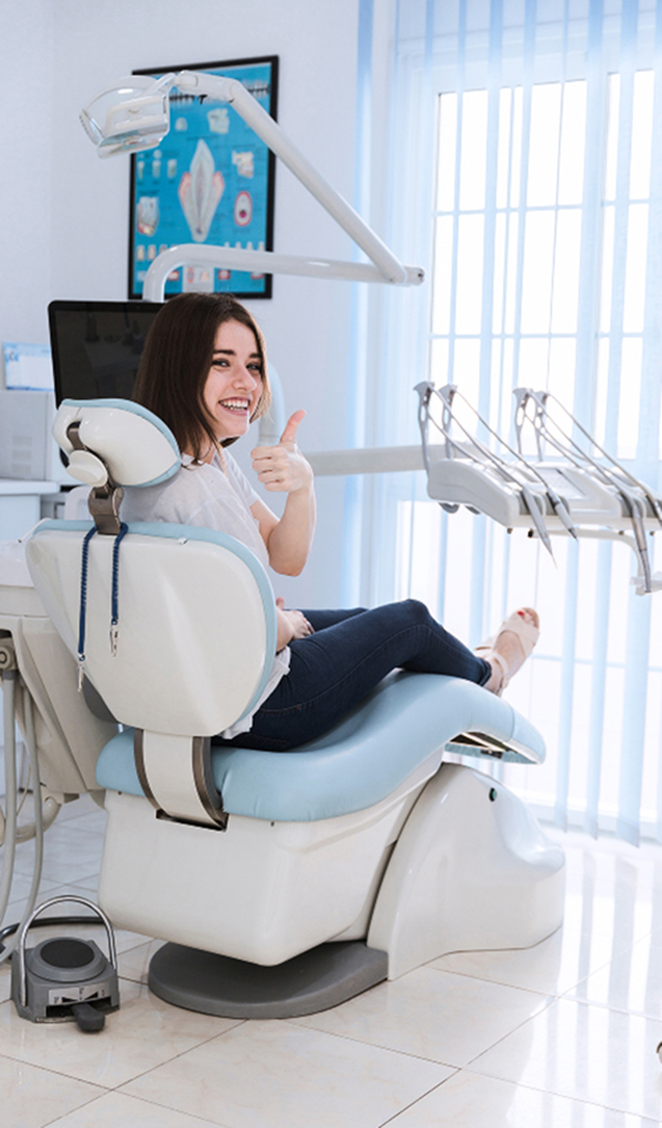 smiling-female-patient-sitting-chair-showing-thumb-up-dental-clinic-1