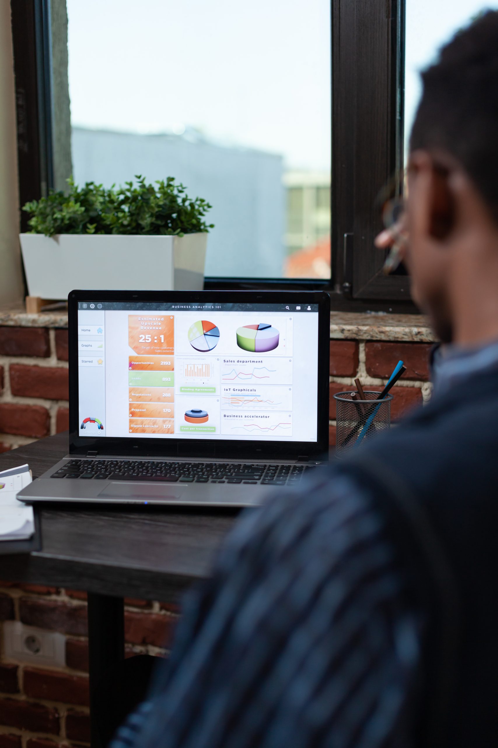 Over shoulder view of startup employee analyzing business key performance indicators on laptop screen